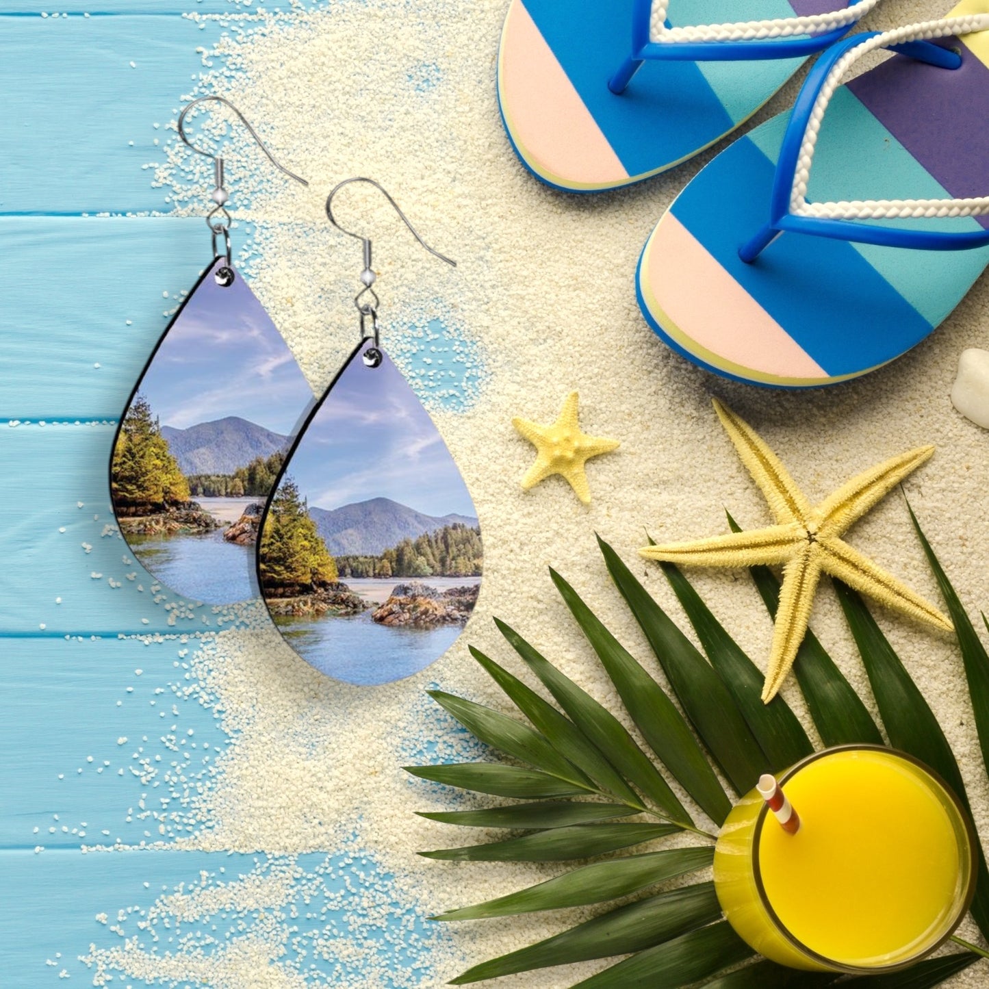 Teardrop-shaped earrings placed on a beach-themed surface with flip-flops and starfish.