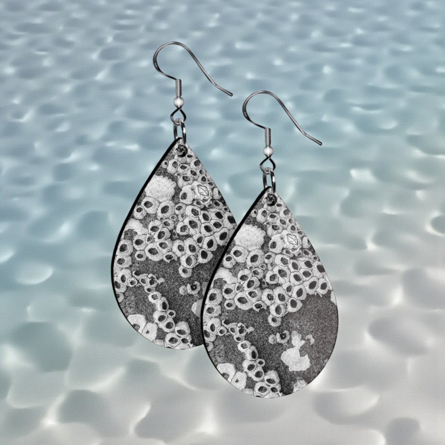 Teardrop-shaped earrings with a black and white pattern on a water background