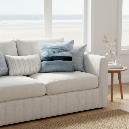 A light beige textured sofa in a bright, modern living room setting with a beach view, styled with several blue and white throw pillows.