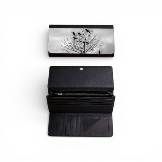 Black wallet with a tree design on the flap, open to show card slots and a pocket.