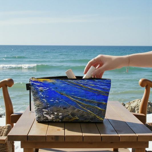 Person reaching into a blue and white bag on a wooden table by the ocean.