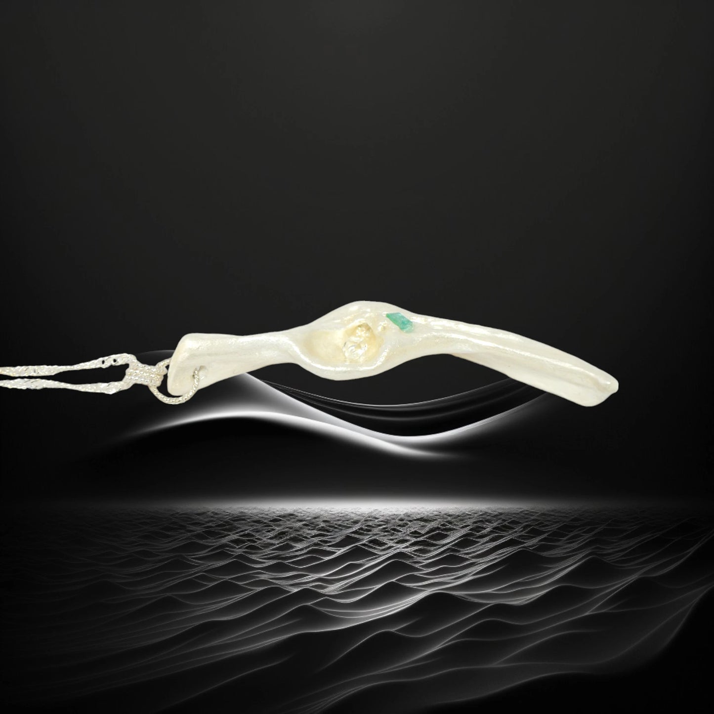 Empress natural seashell pendant with a Herkimer Diamond and Emerald. The pendant is shown on its side on a black wavy background.
