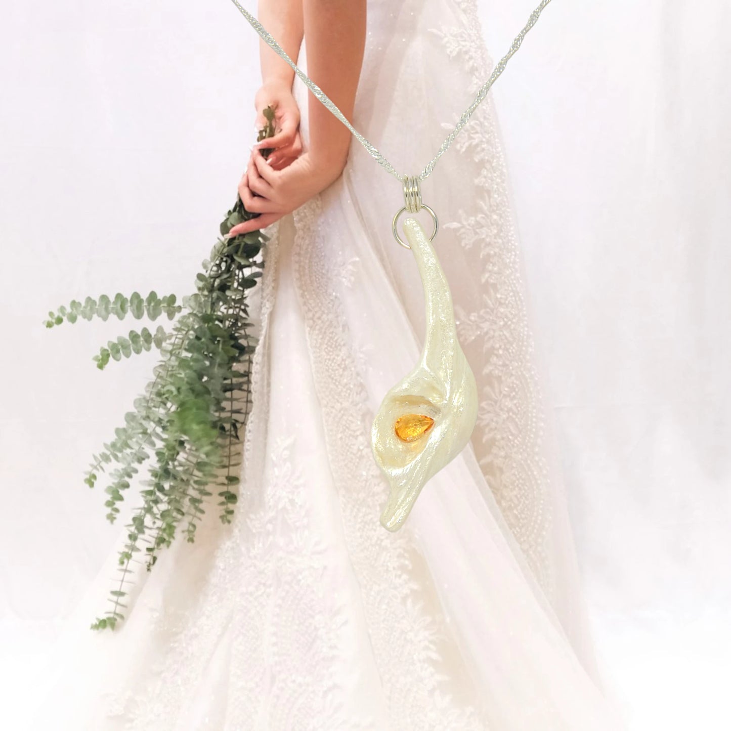 Sun Star natural seashell pendant with a beautiful pear shaped rose cut Citrine. The pendant is shown with a bouquet of greenery and a brides.