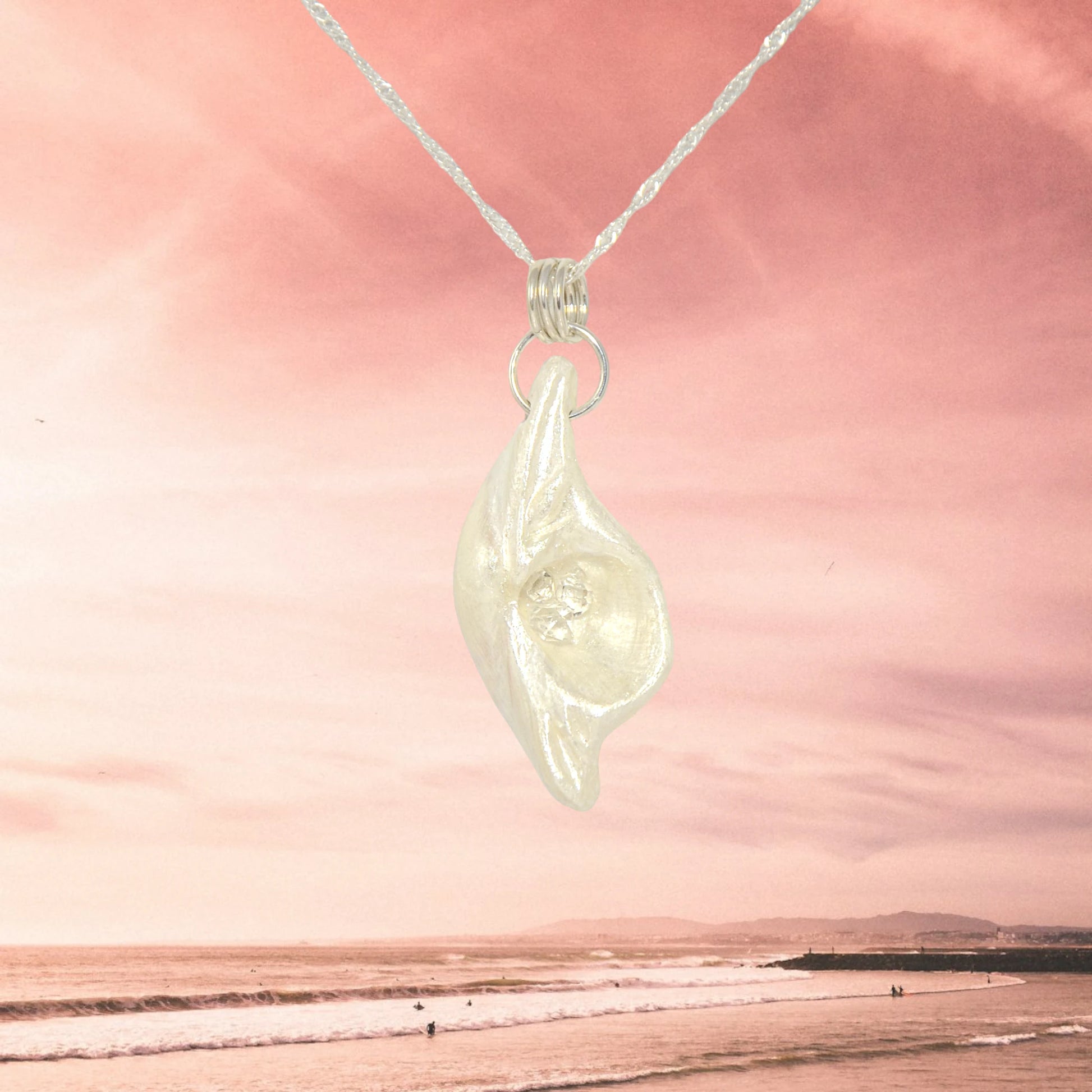 Halo natural seashell pendant with three herkimer diamonds. The pendant is shown with a pink sky and ocean waves.
