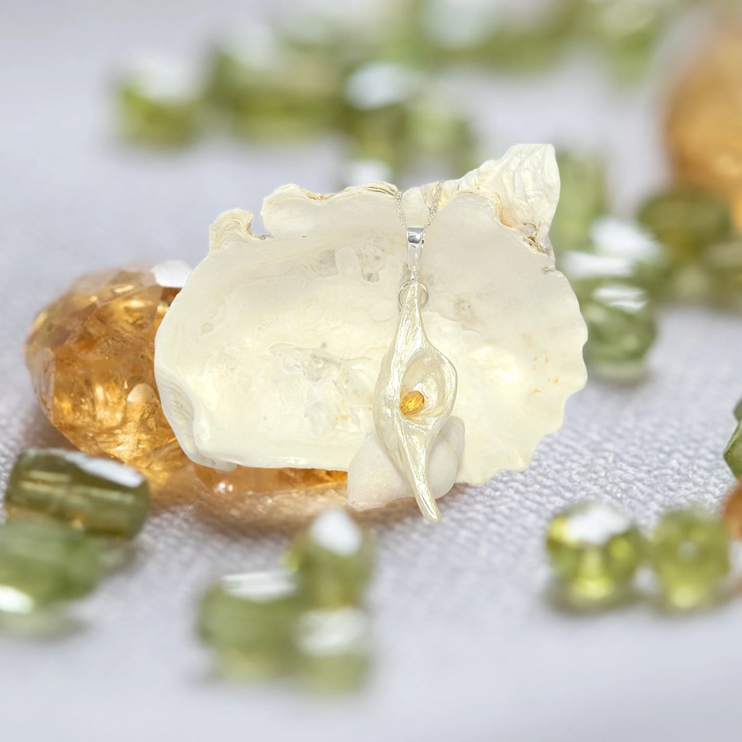 Lightmaker natural seashell pendant A beautiful pear shaped rose cut Citrine compliments the pendant. The pendant is shown in front of a larger seashell with citrine and peridot.