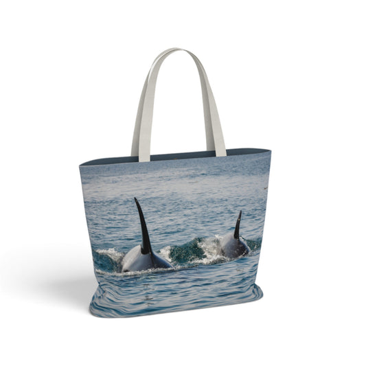 A tote bag with white handles, featuring a photographic print of two orcas surfacing from the ocean on the front, set against a plain white background.