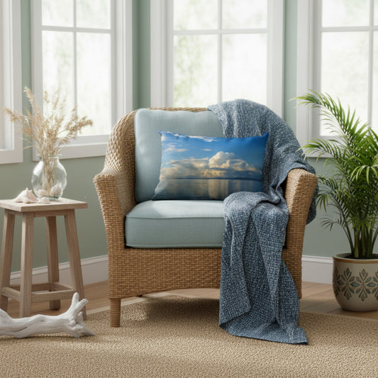 A woven armchair with light blue cushions sits in a bright room with green walls, a blue throw blanket draped over the arm, and a matching blue pillow featuring a cloud-and-water landscape print.