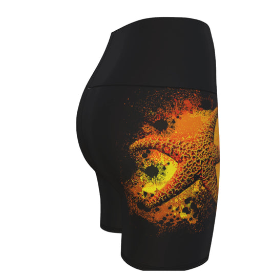 Starfish Orange Yoga Shorts features a orange starfish on a bed of abstract sand on black shorts.