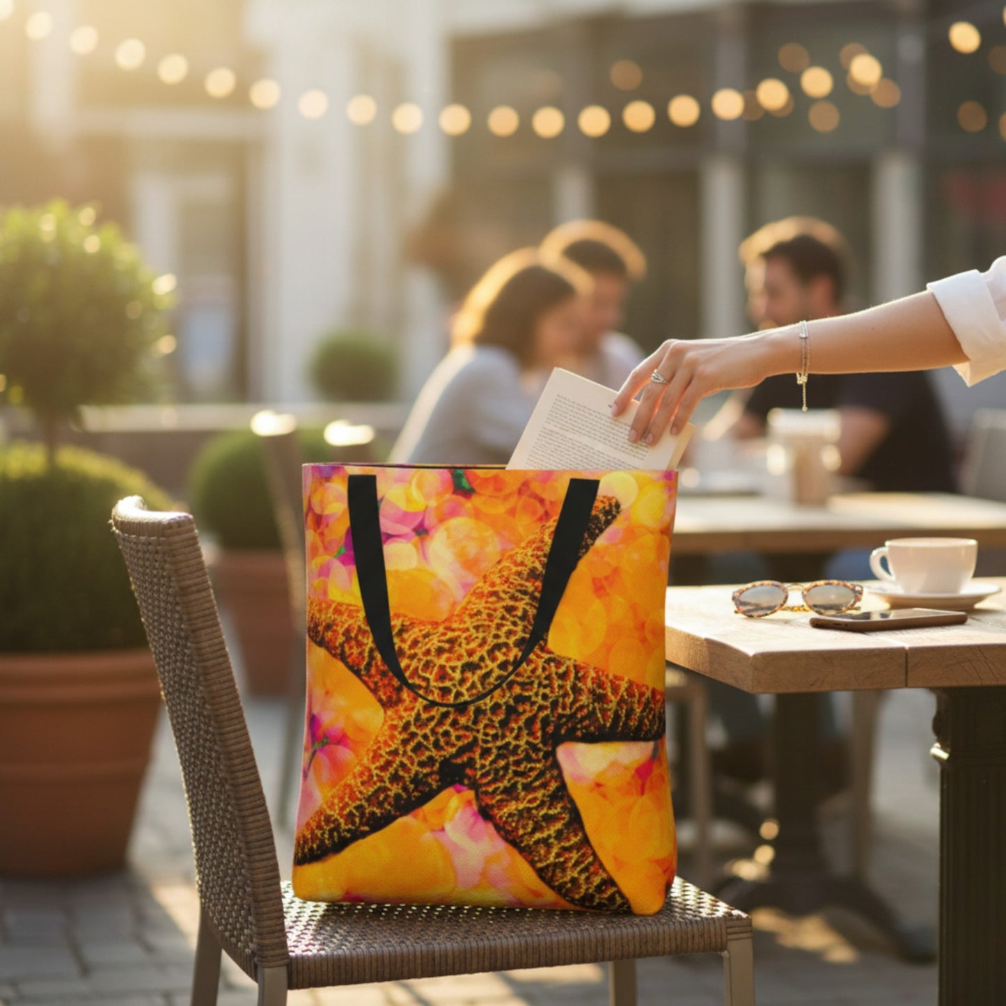 Person holding a colorful tote bag with a starfish design in an outdoor setting.