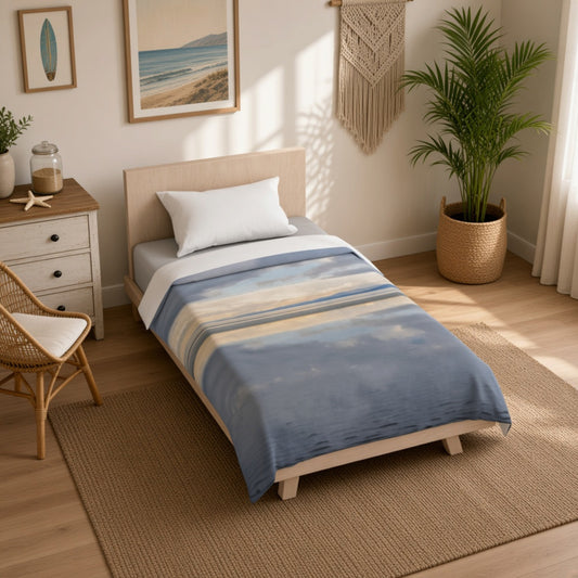 A single bed dressed in a blue and beige striped blanket, styled in a bright, modern bedroom with a wooden floor, rattan chair, and potted palm.