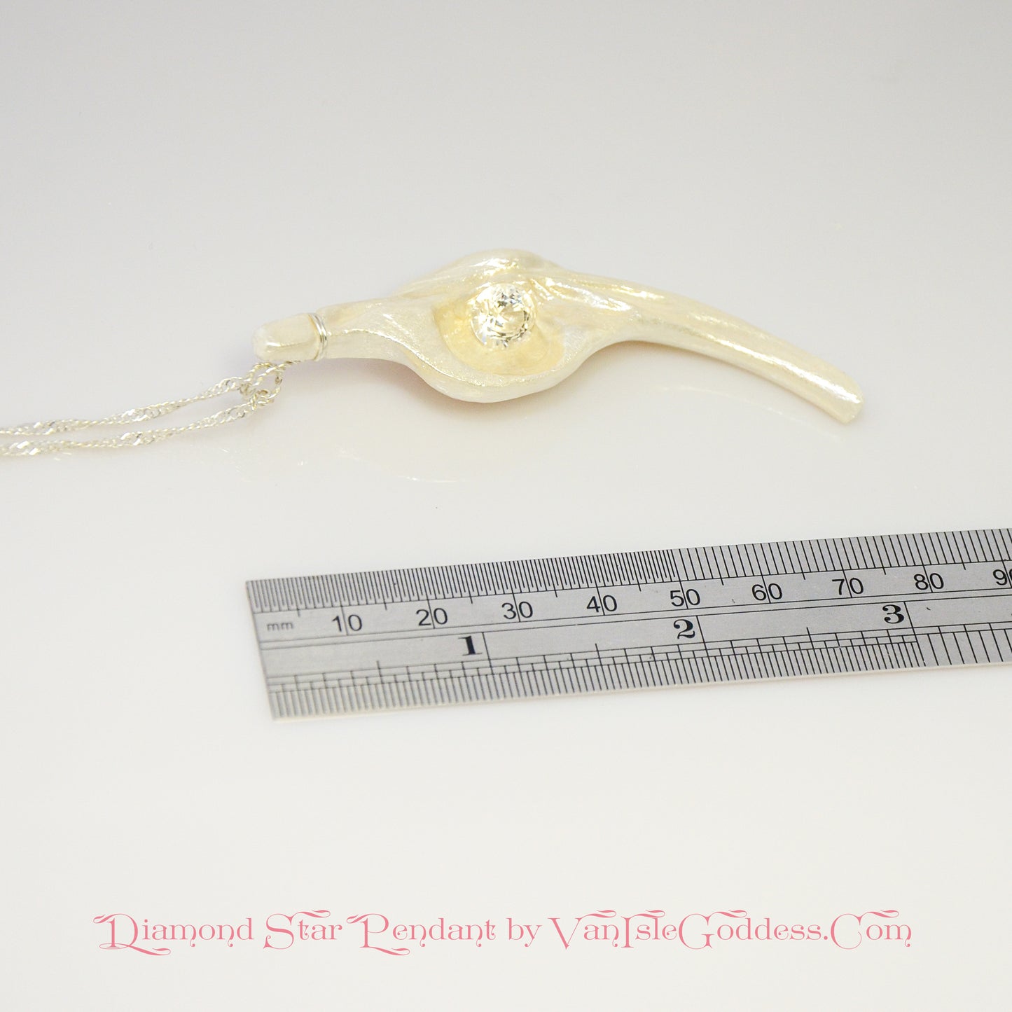 Diamond Star natural seashell pendant with eight mm faceted herkimer diamond. The pendant is shown laying along a ruler so the viewer can see the length of the pendant.