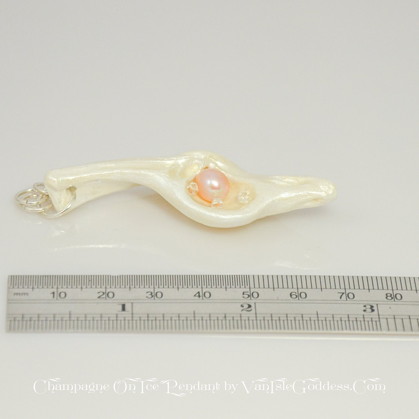 The pendant is shown laying on its side along a ruler so the viewer can see the length of the pendant.