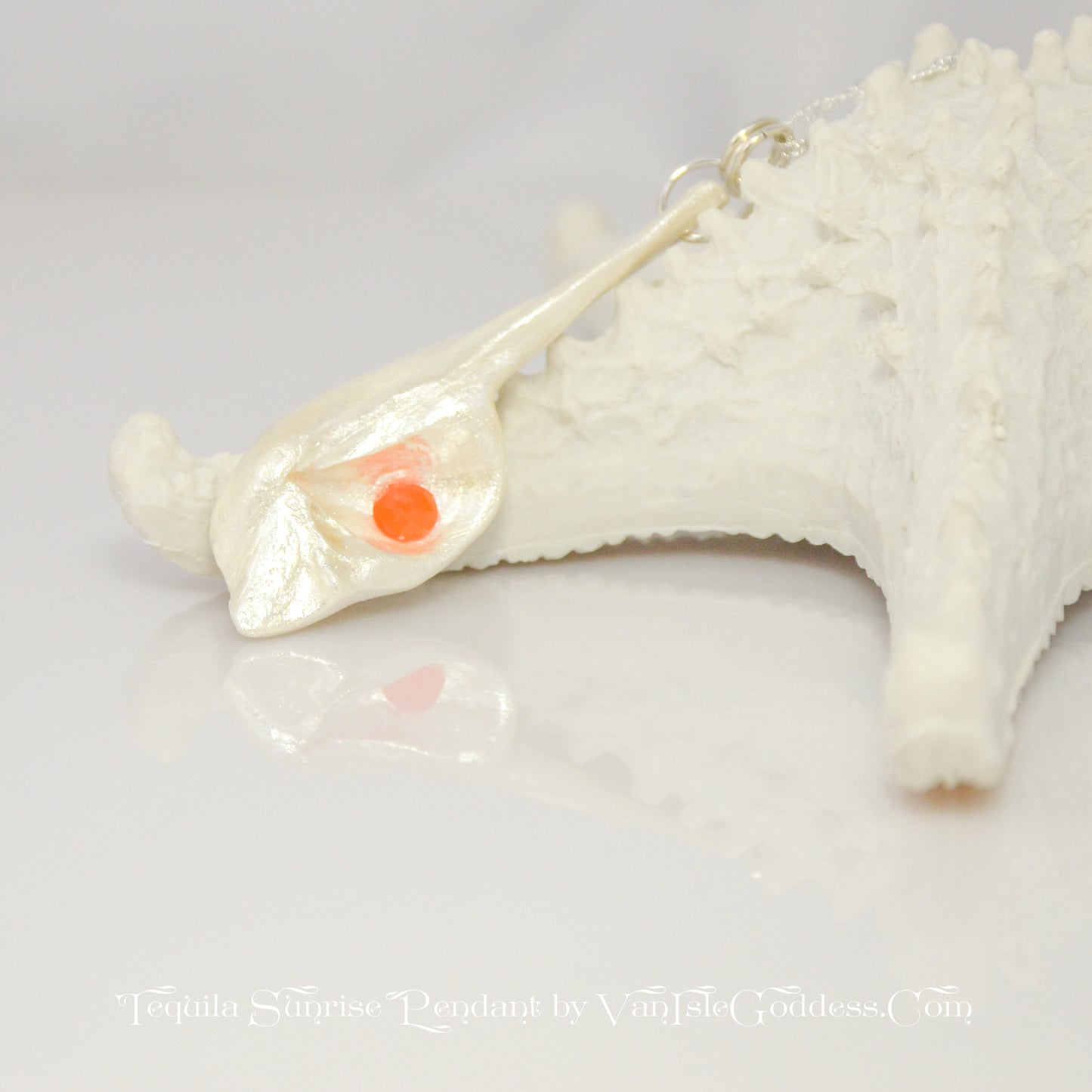 Tequila Sunrise natural seashell pendant a rose cut Carnelian gemstone. The pendant rests against a starfish. The words on the bottom of the image say: Tequila Sunrise pendant by Van Isle Goddess dot com
