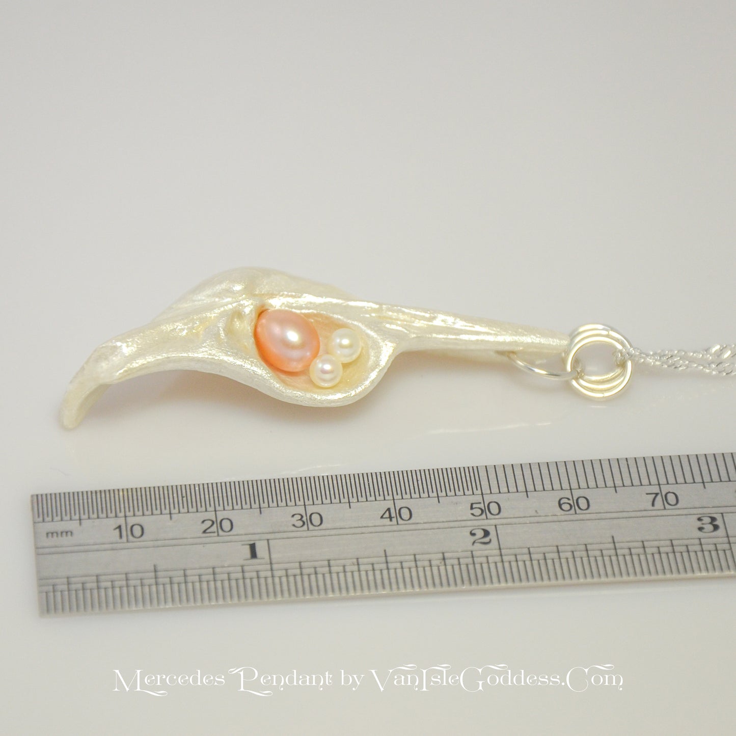 This natural seashell pendant has a real 7-8mm pink freshwater pearl and two baby pearls. The pendant is shown along side a ruler so the viewer can see the length of the pendant.