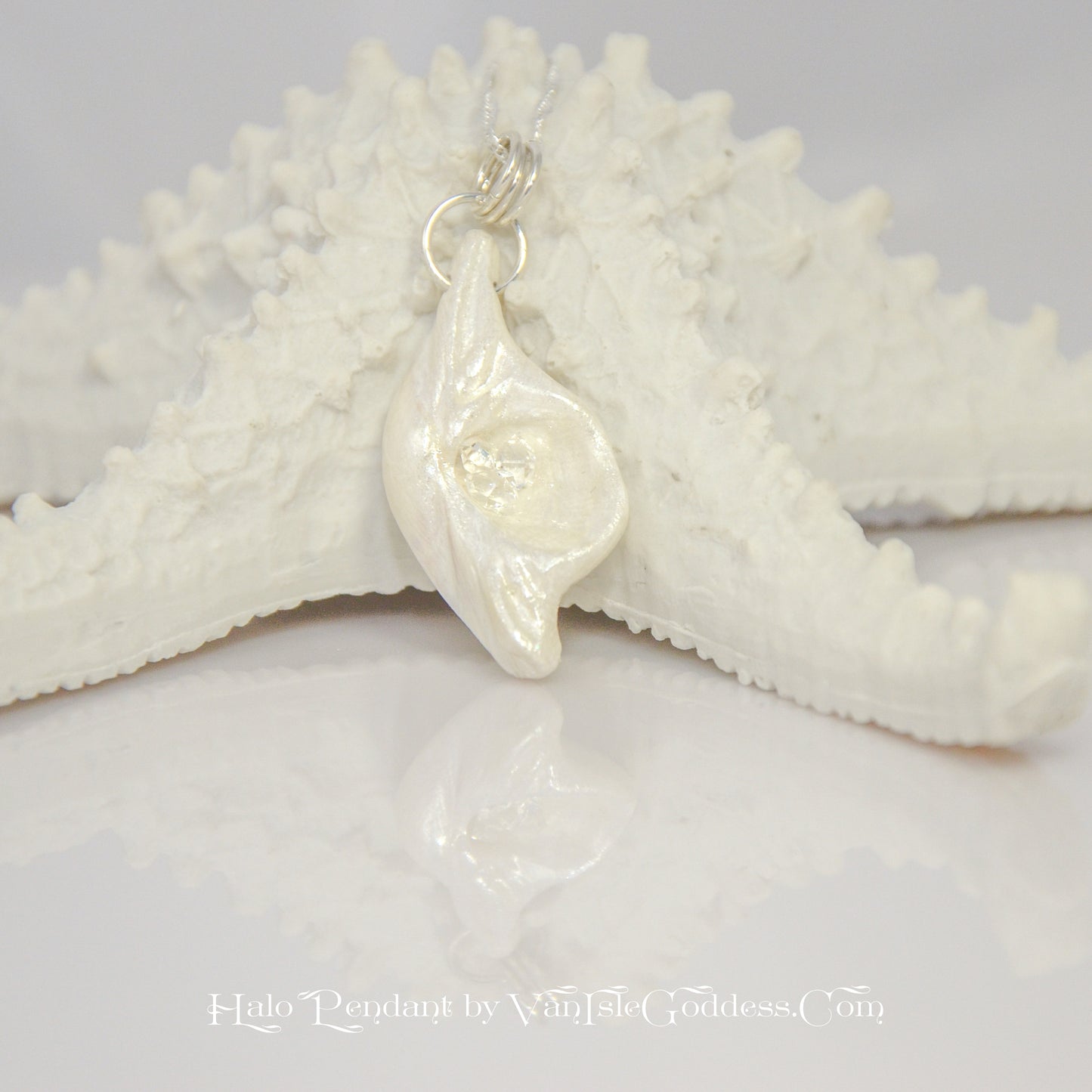 Halo natural seashell pendant with three herkimer diamonds. The pendant is shown resting on a starfish.