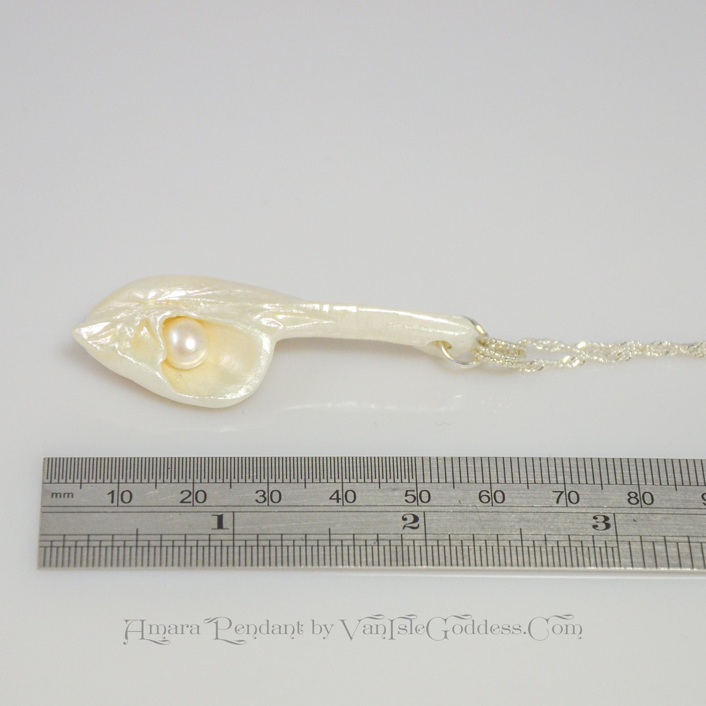 Amara is the name of this one of a kind pendant made from a natural seashell from the beach of Vancouver Island. The pendant has a real freshwater pearl. The pendant is being shown along side a ruler indicating the size of the pendant.