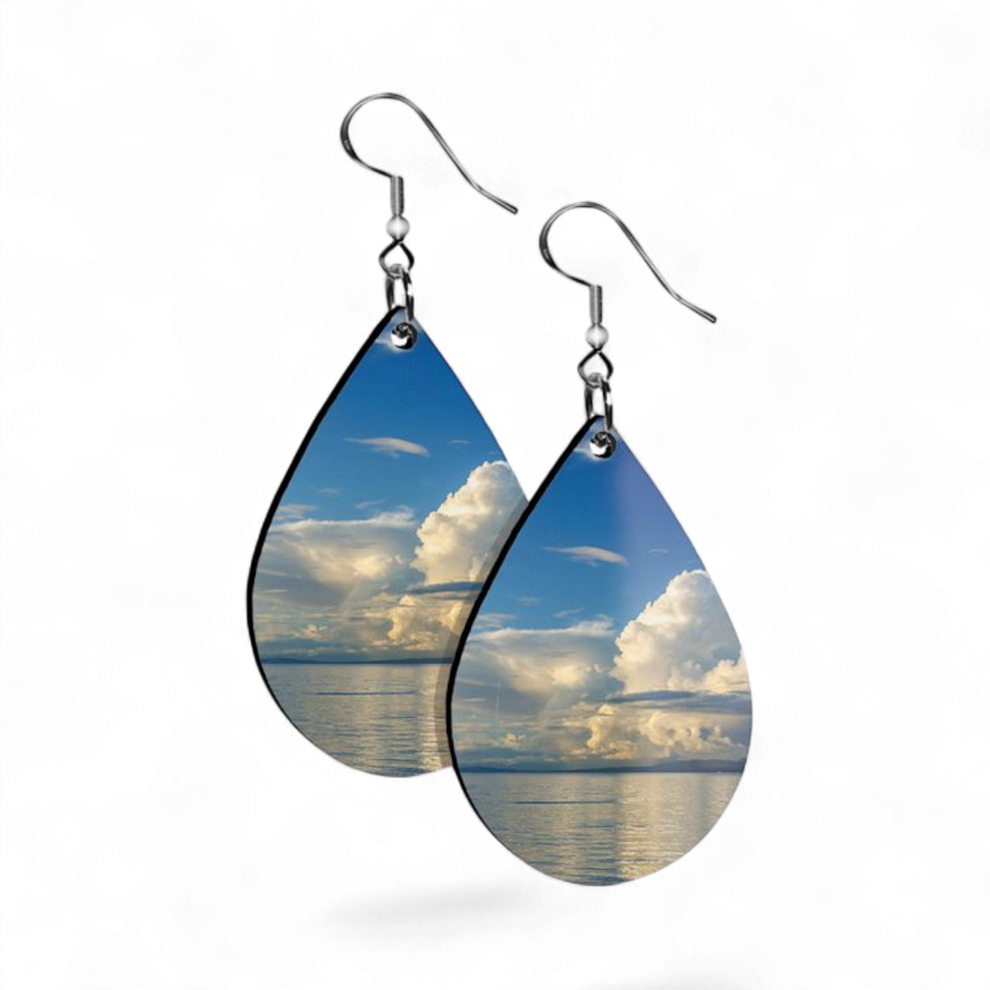 Teardrop-shaped earrings with a scenic design of clouds and water on a white background