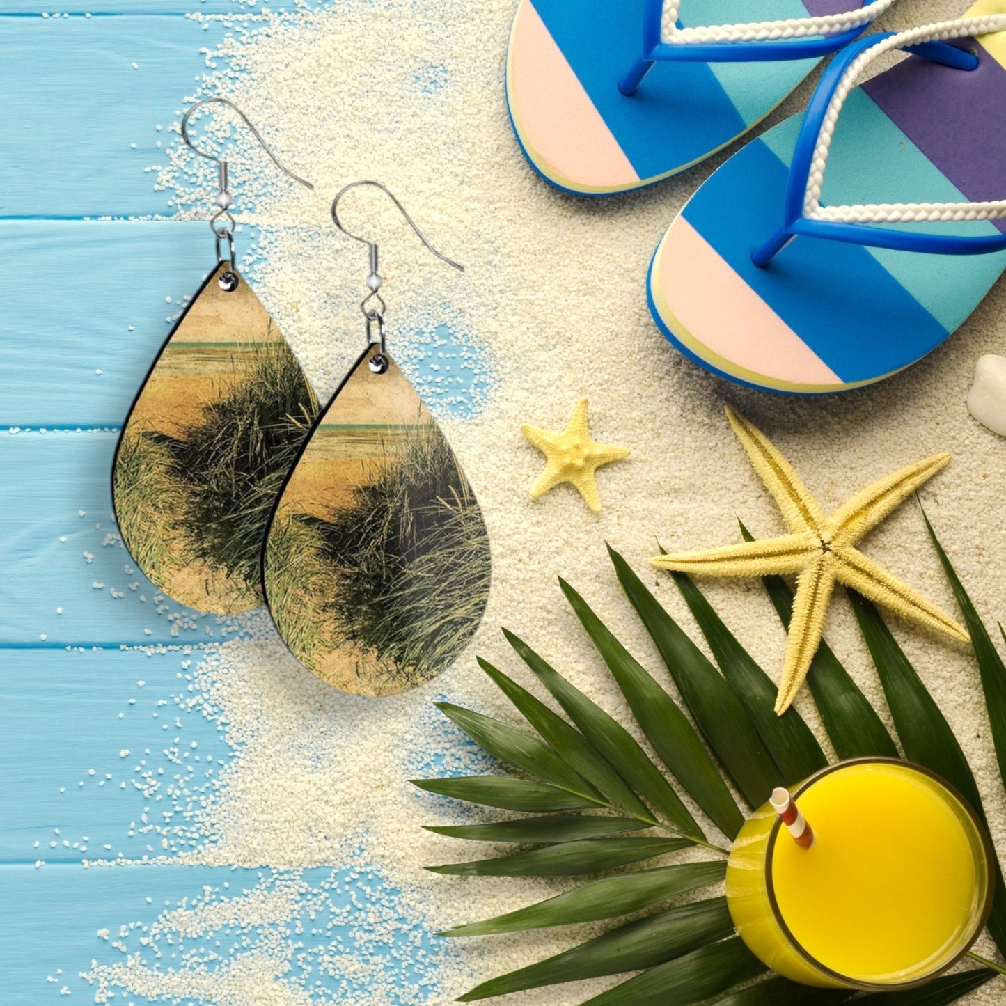 Teardrop-shaped earrings on a beach-themed background with flip-flops, starfish, and a drink.