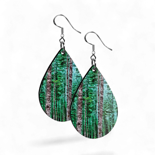 Teardrop-shaped earrings with forest design on a white background