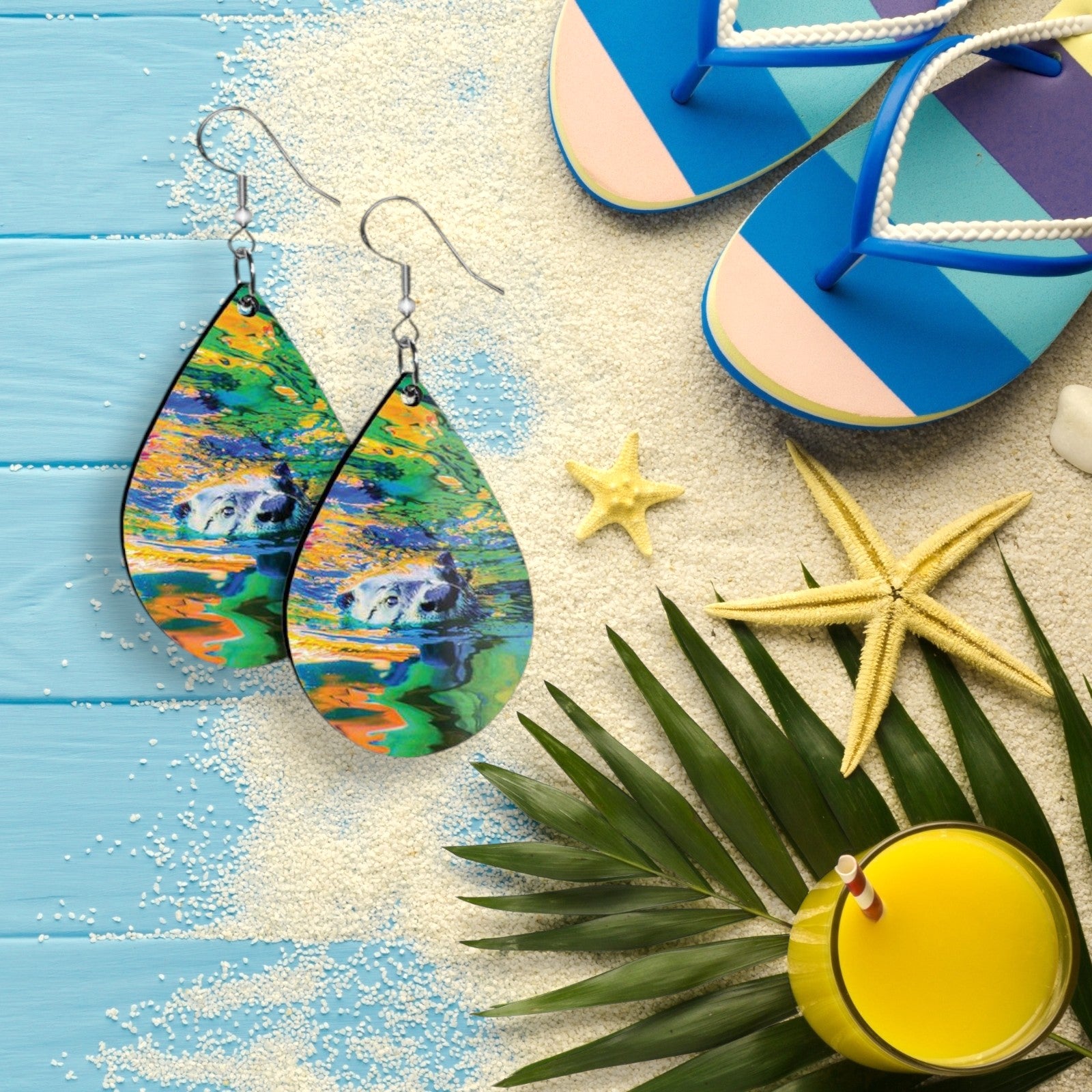 Colorful teardrop-shaped earrings on a beach-themed background with flip-flops, starfish, and a drink.