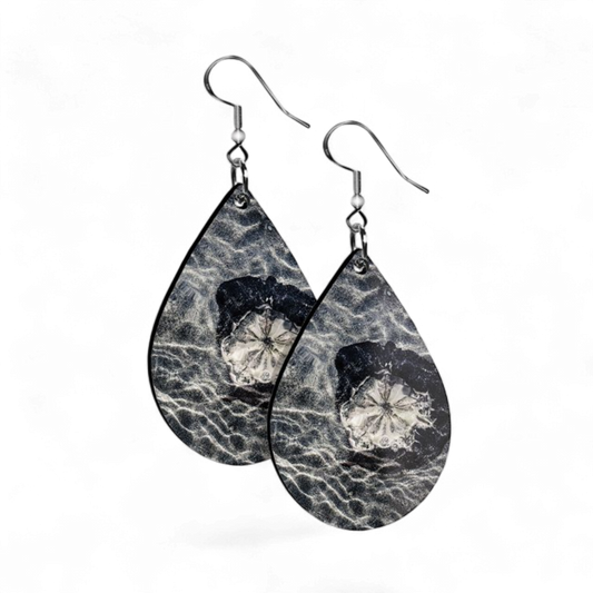 Teardrop-shaped earrings with black and white sand dollar  design on a white background