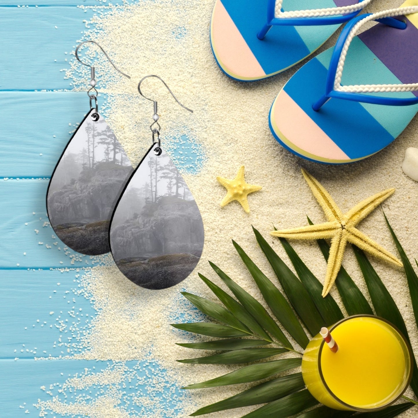 Teardrop-shaped earrings on a beach-themed background with flip-flops, starfish, and a drink.