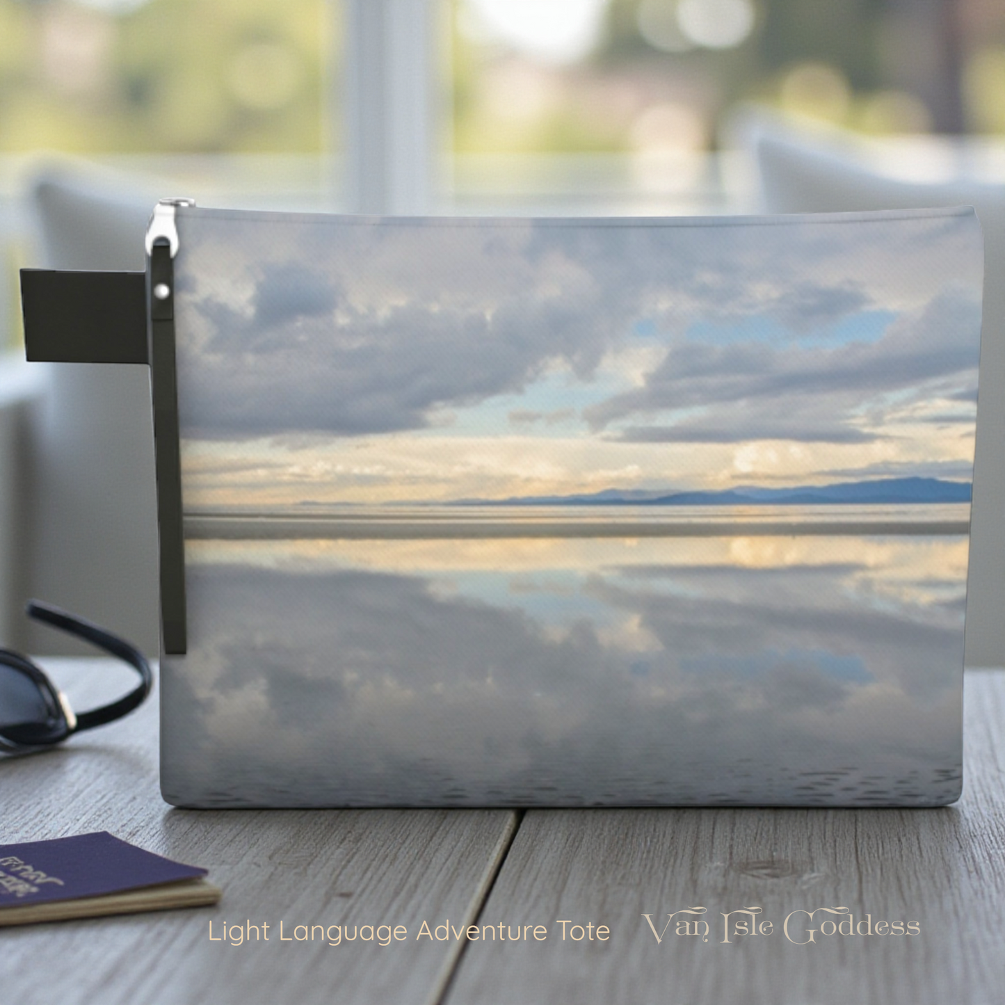 pouch with a scenic design of clouds and water, placed on a surface with sunglasses and a passport.