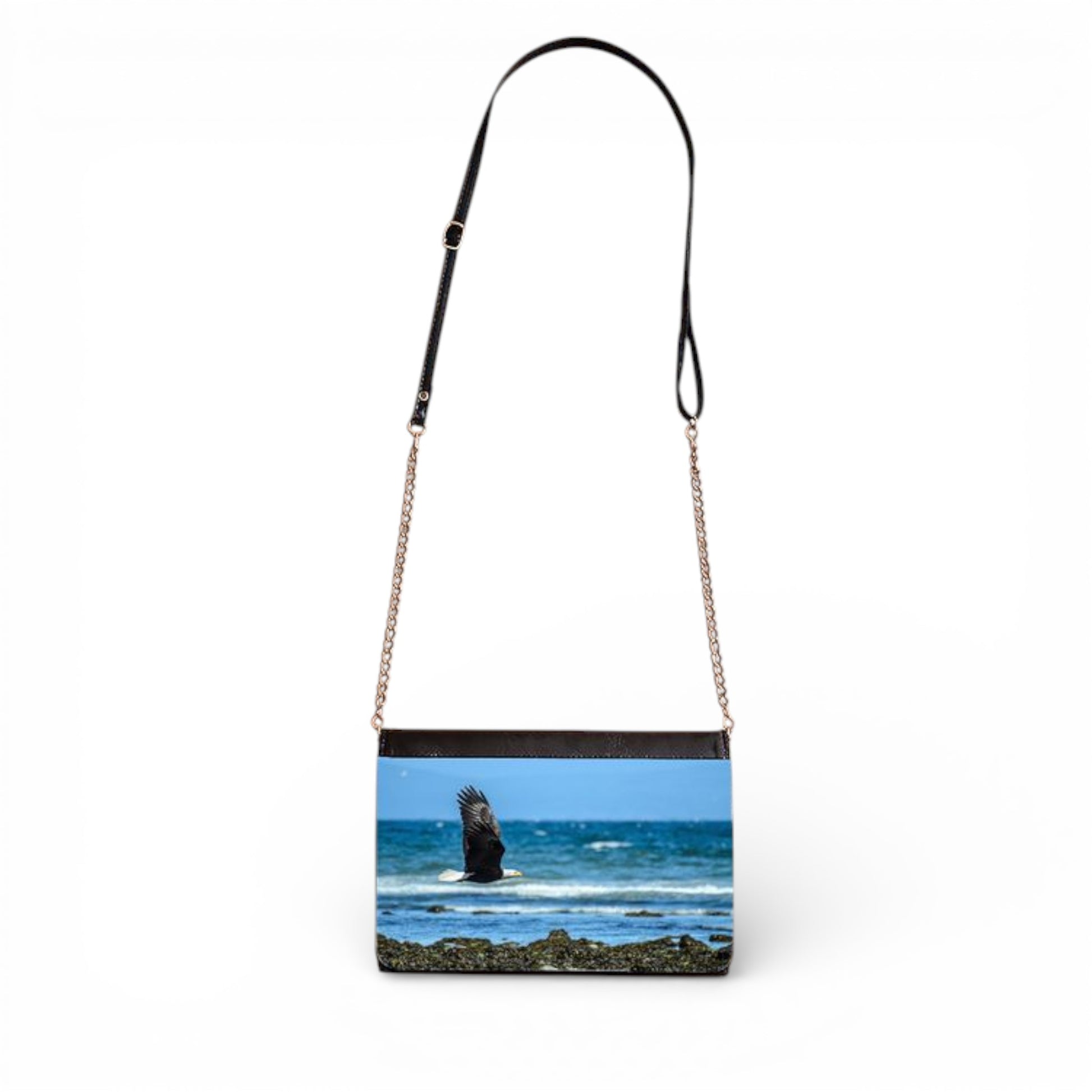 Crossbody bag with a scenic print of a beach and rock formation.