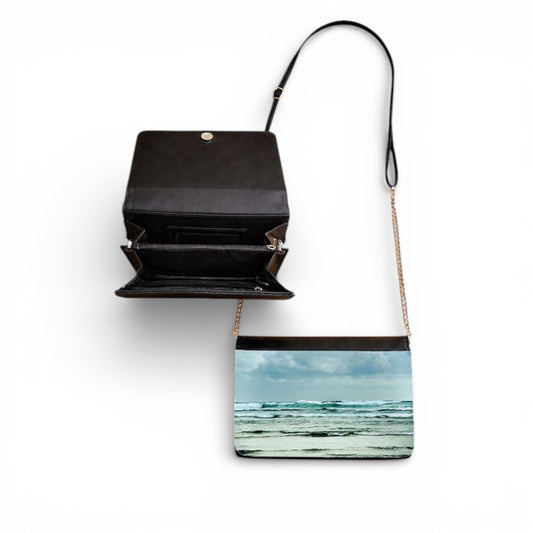 Black handbag with a beach scene print on a white background