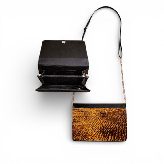 Black handbag with a brown sand at sunset on a white background
