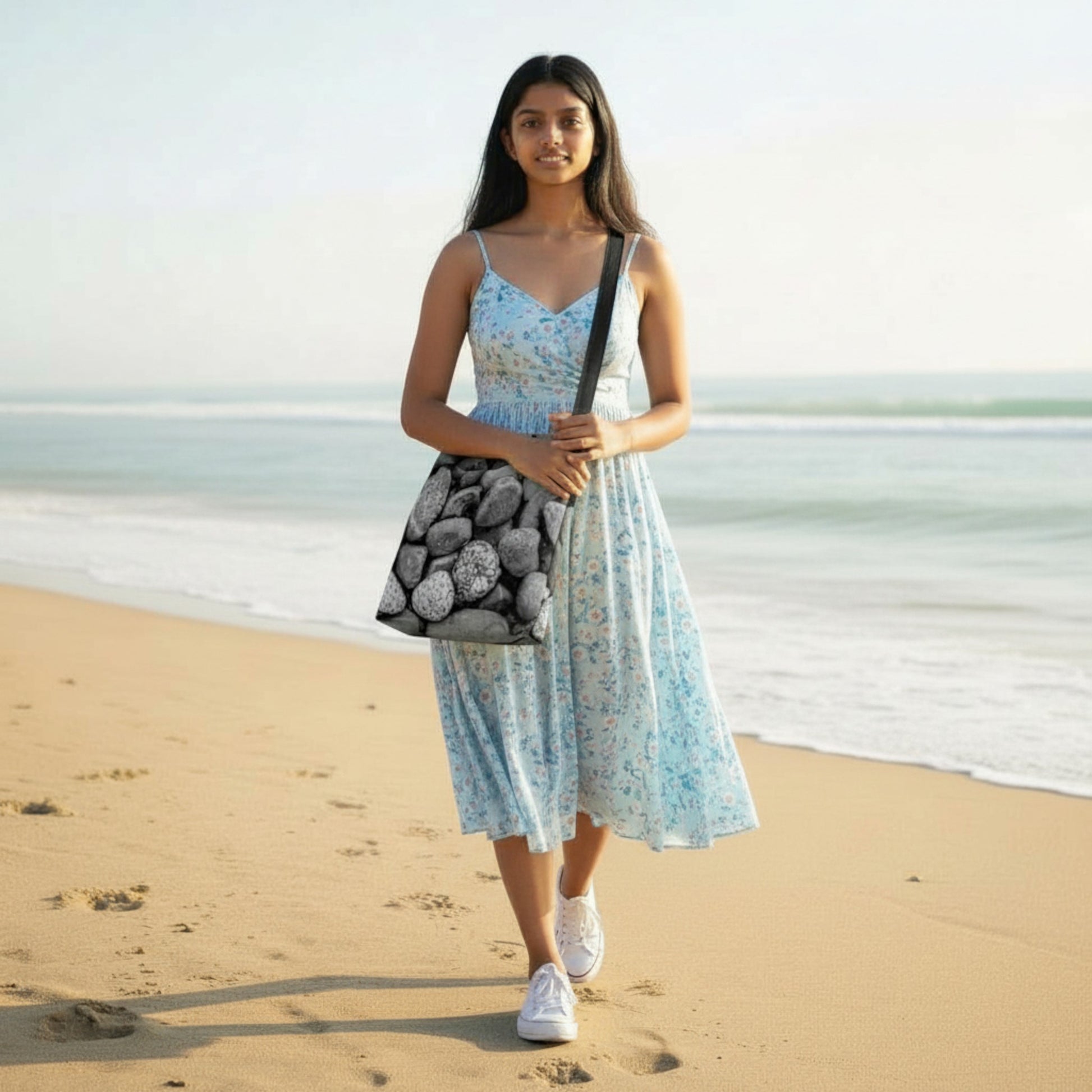 Woman in a floral dress holding a patterned bag on a beach