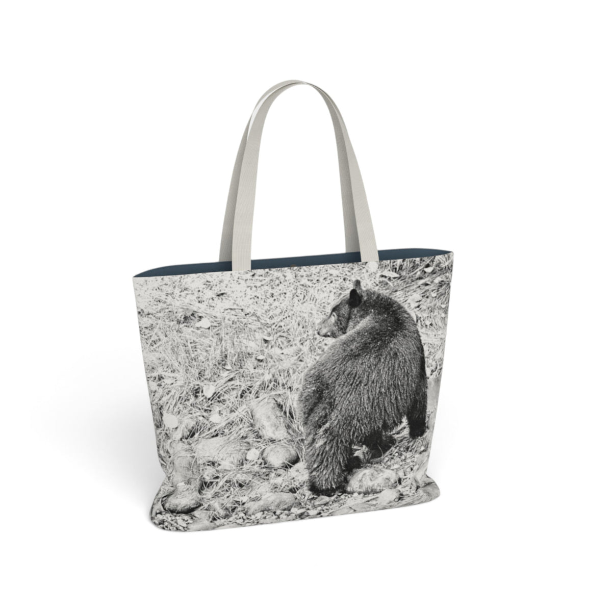 A tote bag featuring a black and white photograph of a bear on the front, with light beige shoulder straps and a dark navy blue interior lining, shown against a plain white background.