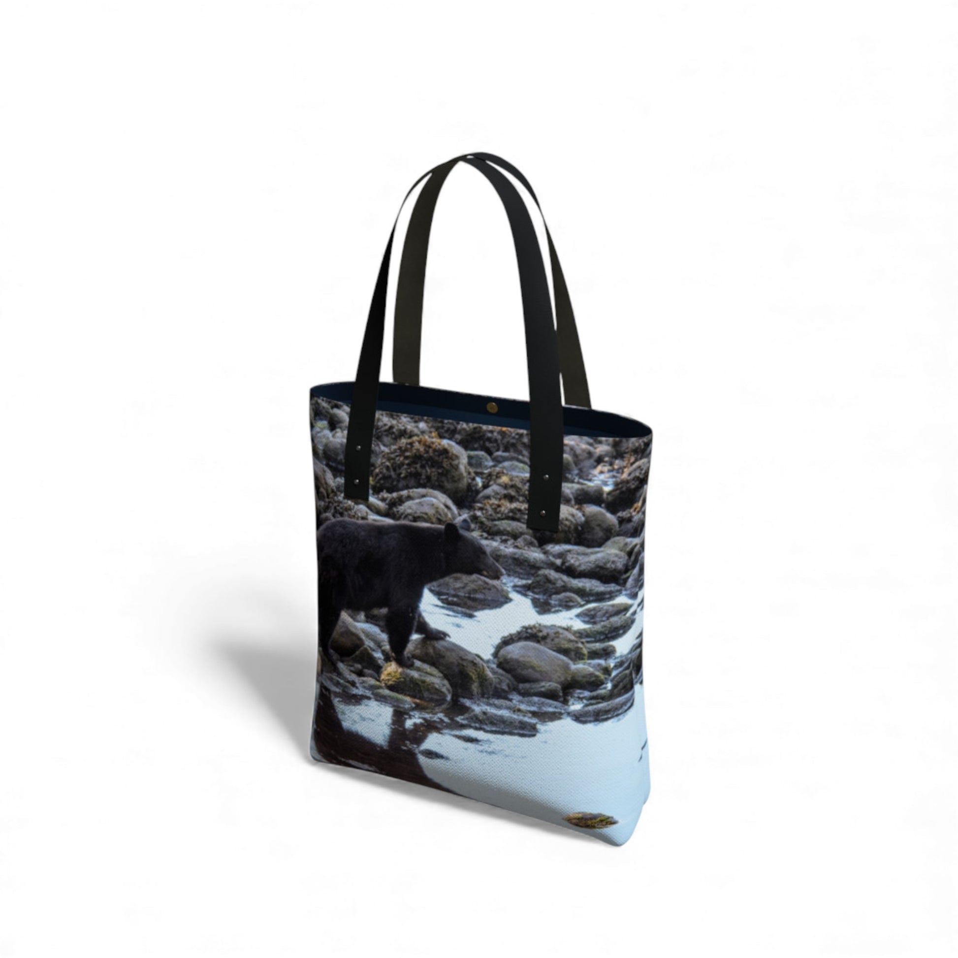 Tote bag with a design of a bear on rocks by a body of water.