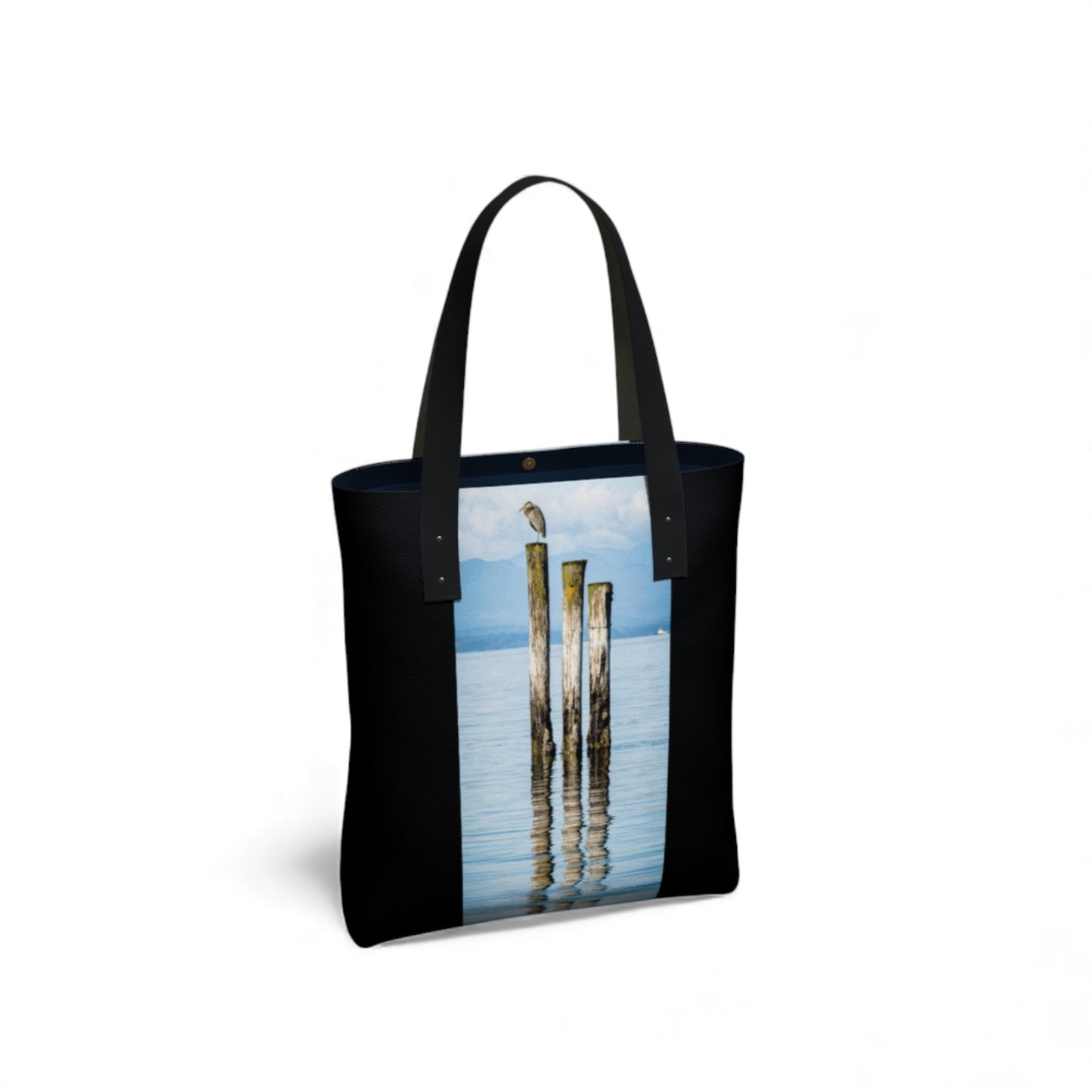 Tote bag with a design of beach poles with a blue heron at the top reflected in water on a white background