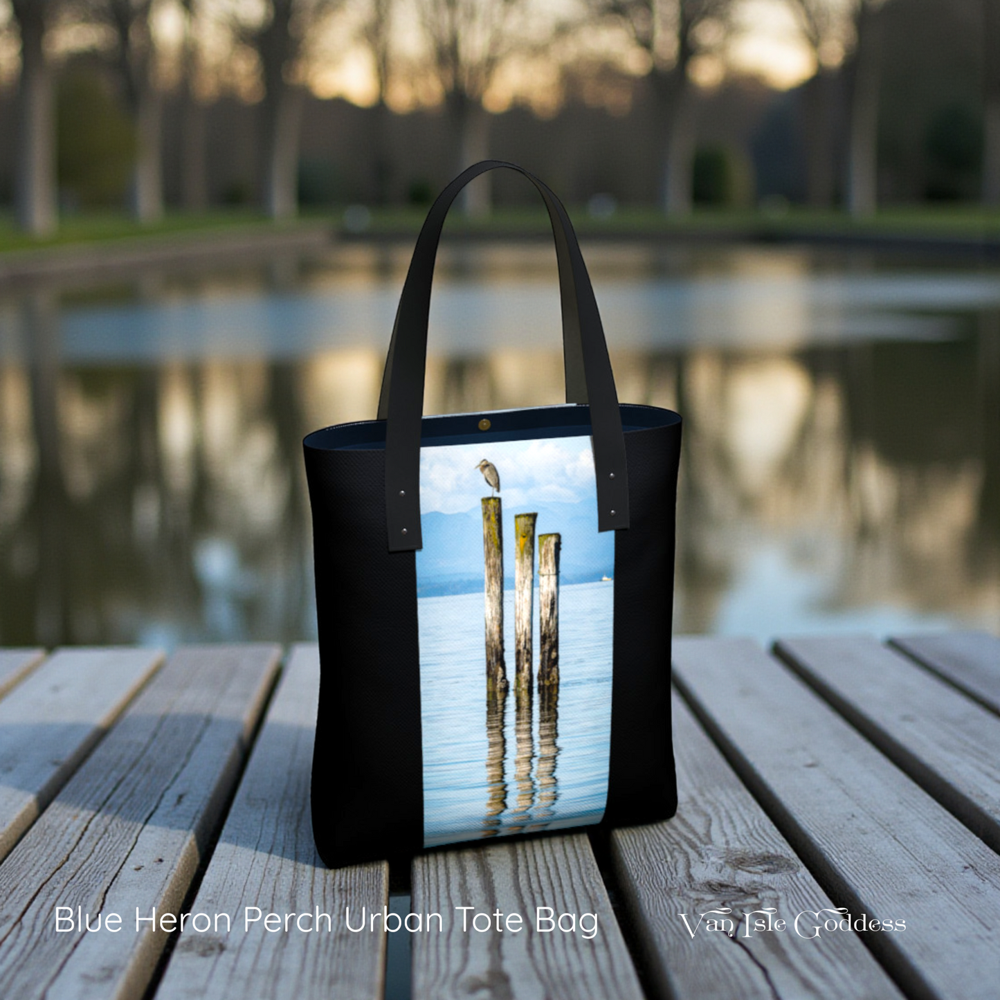 Black tote bag with a scenic design on a wooden dock by a body of water.