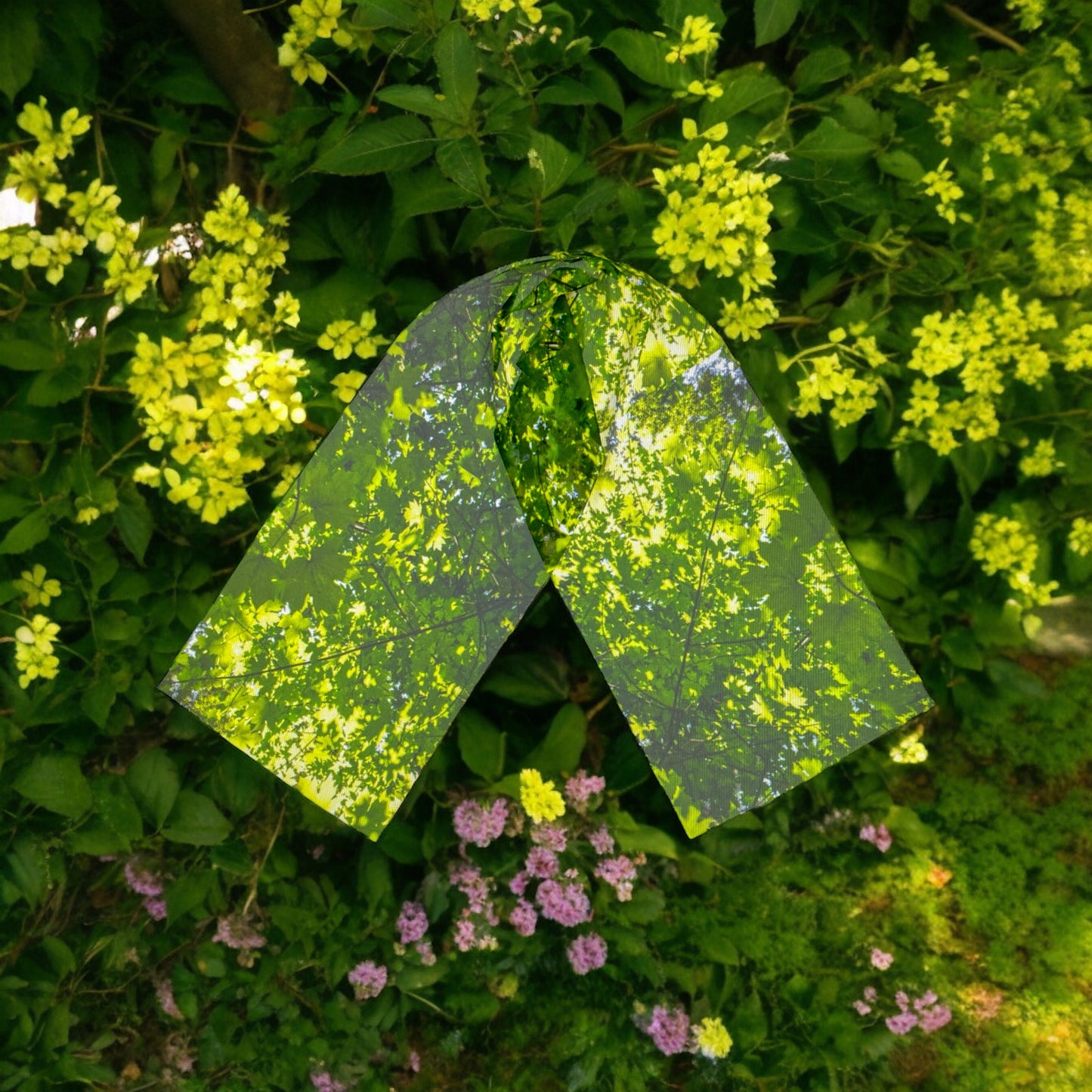 Canopy of Leaves Long Scarf resting on a background of greenery.