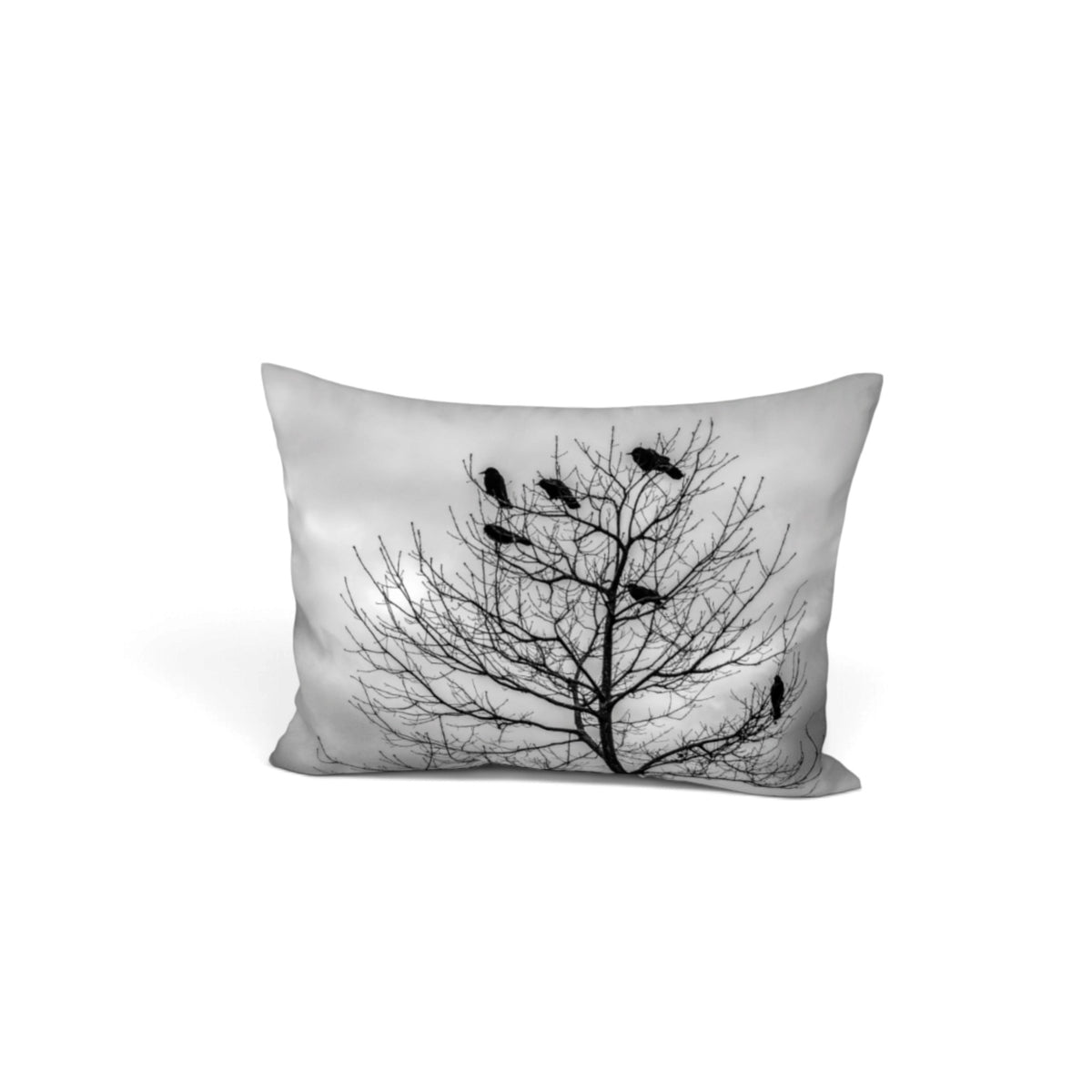 A square decorative throw pillow featuring a black and white photographic print of a bare tree silhouette with several birds perched on the branches, shown against a plain white background.