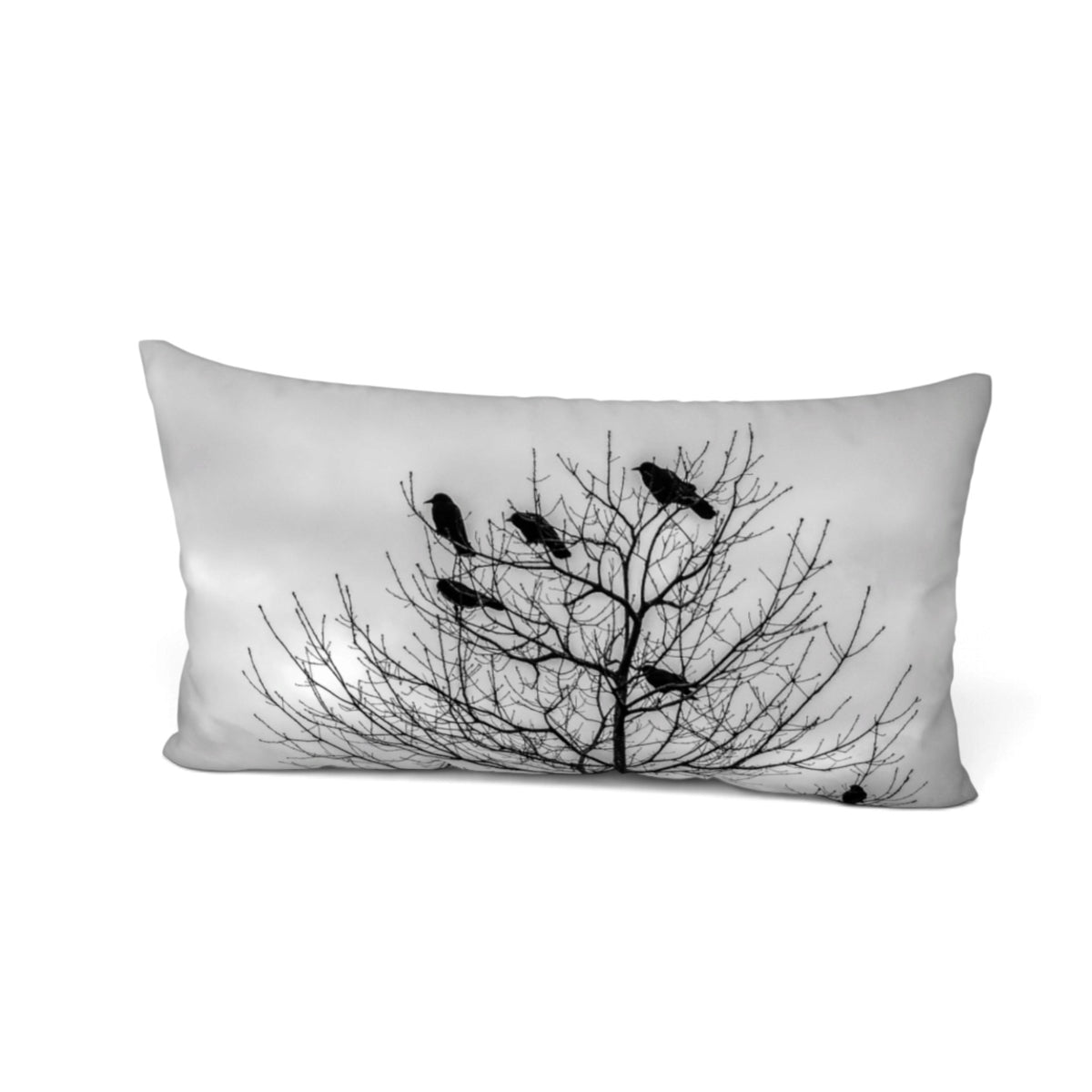 A rectangular lumbar pillow featuring a black and white photographic print of a bare tree silhouette with several birds perched on its branches, set against a plain white background.