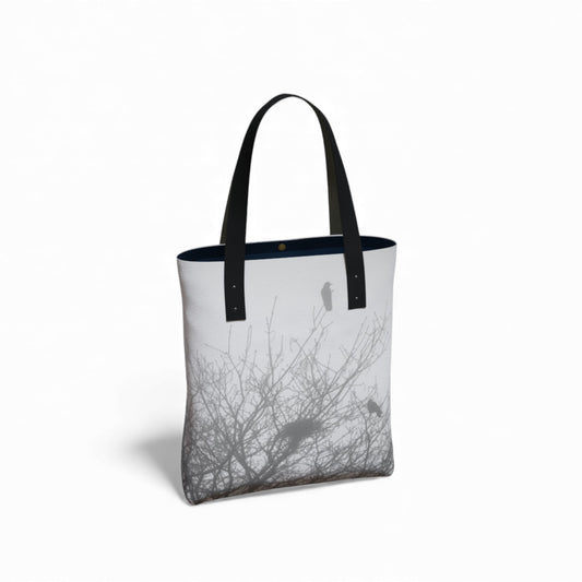 Tote bag with black handles and a design of birds on branches on a white background