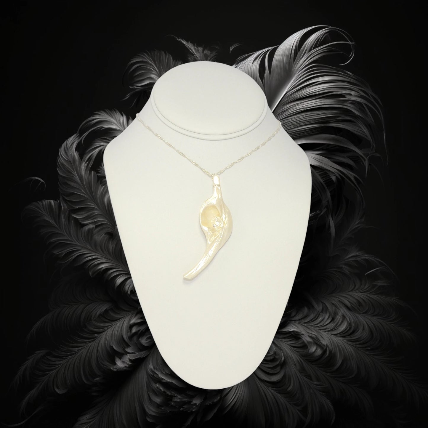Diamond Star natural seashell pendant with eight mm faceted herkimer diamond. The pendant is shown hanging from a chain on a necklace displayer.  The background is black with an array of leaves.