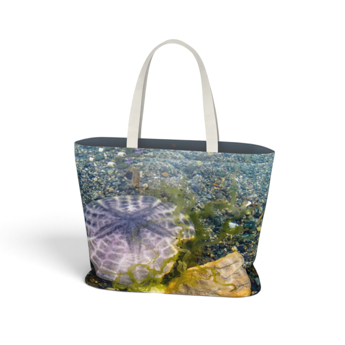 A tote bag featuring an all-over print of an underwater scene with a sea urchin, blue water, and green seaweed, complete with two white shoulder straps, shown on a plain white background.