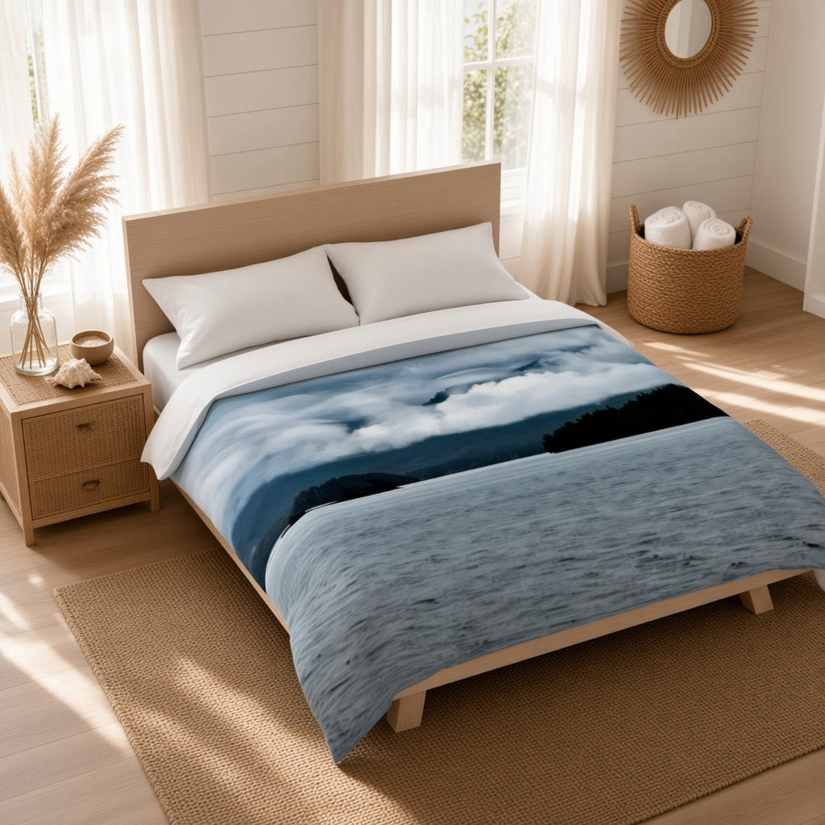 A bed dressed in a blue and white landscape-print duvet cover with a wood headboard, styled in a bright, modern bedroom with a nightstand, woven rug, and natural light.