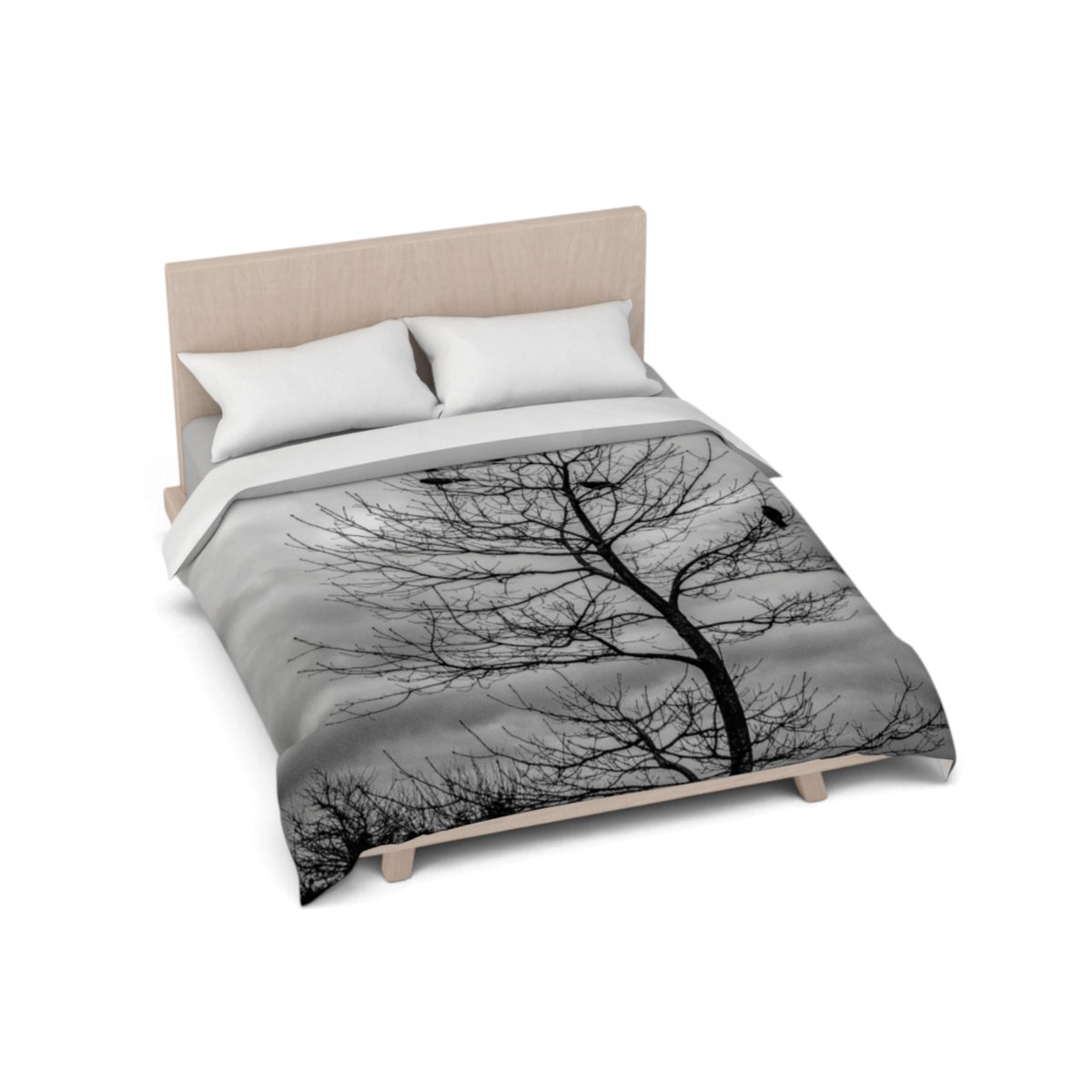 A bed with a light wood frame and white pillows, shown from an elevated angle on a white background. The duvet cover features a black and gray photographic print of a bare tree against a cloudy sky.