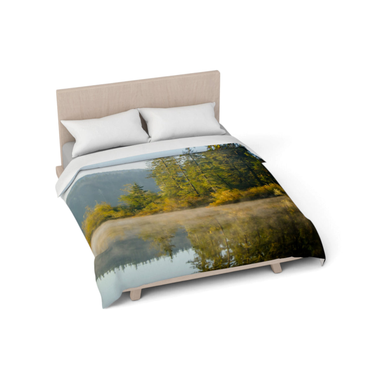 A bed with a printed duvet cover featuring a scenic forest and lake reflection design, styled with two white pillows and a light wood headboard on a white background.