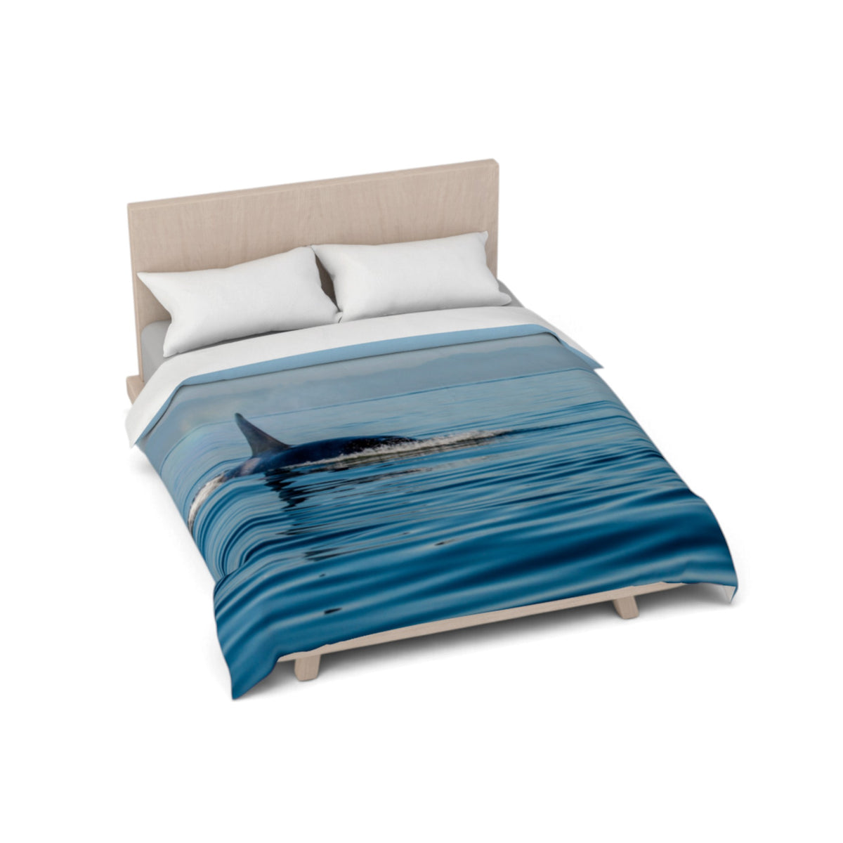 A bed with a duvet cover featuring a blue ocean scene with a dolphin, styled with two white pillows and a light wood headboard, shown on a plain white background.