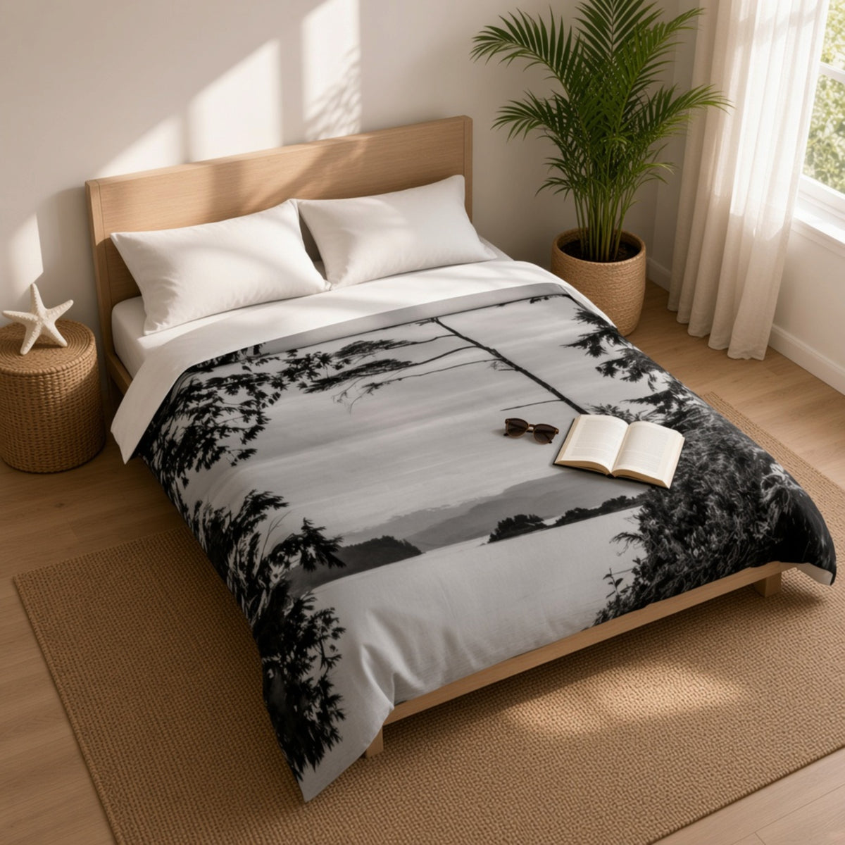 A twin bed dressed in a black-and-white scenic duvet cover featuring a tree-lined path, styled in a bright, modern bedroom with a wooden headboard, white pillows, a potted plant, and an open book on the duvet.