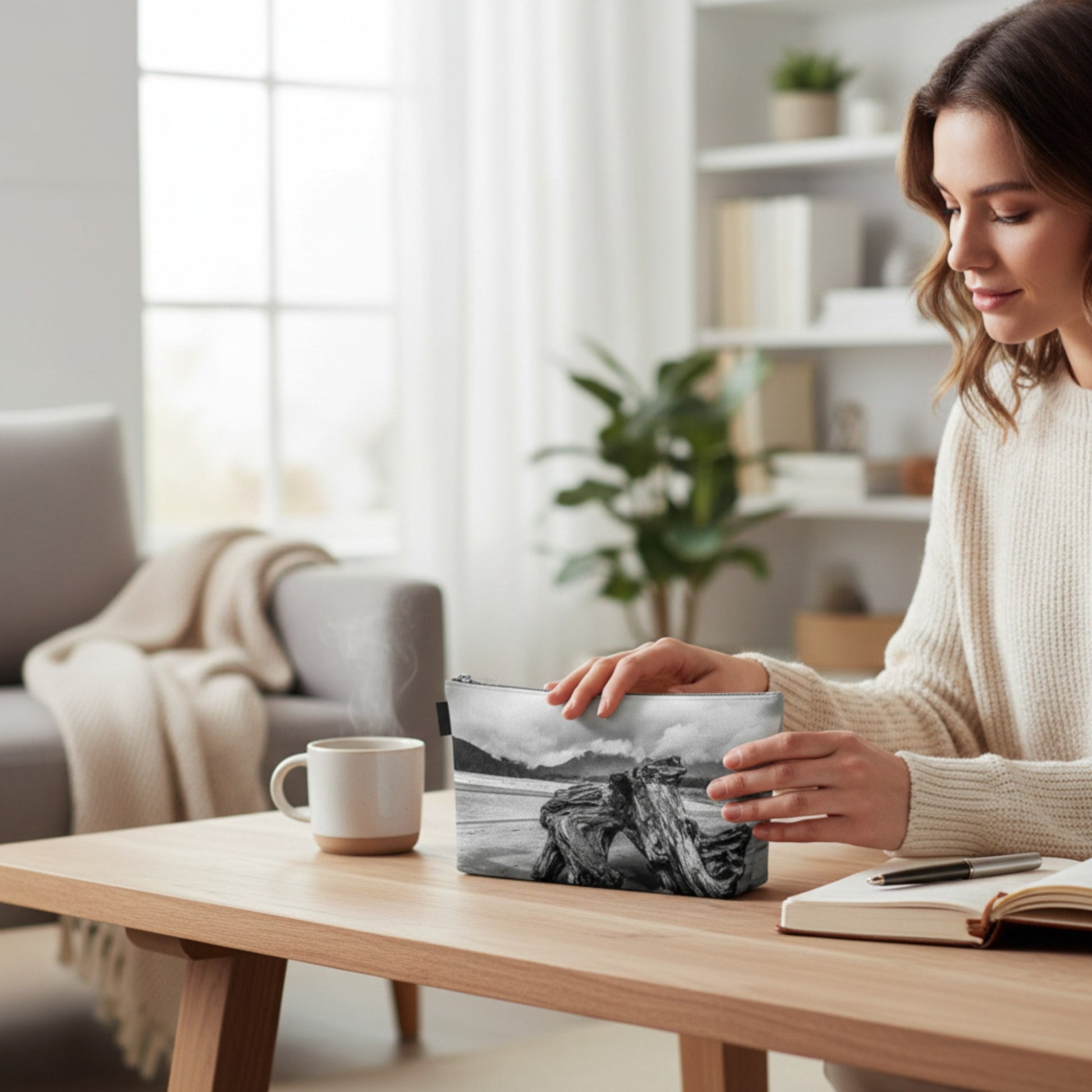 Woman in a cozy living room with a coffee mug and notebook on a table.