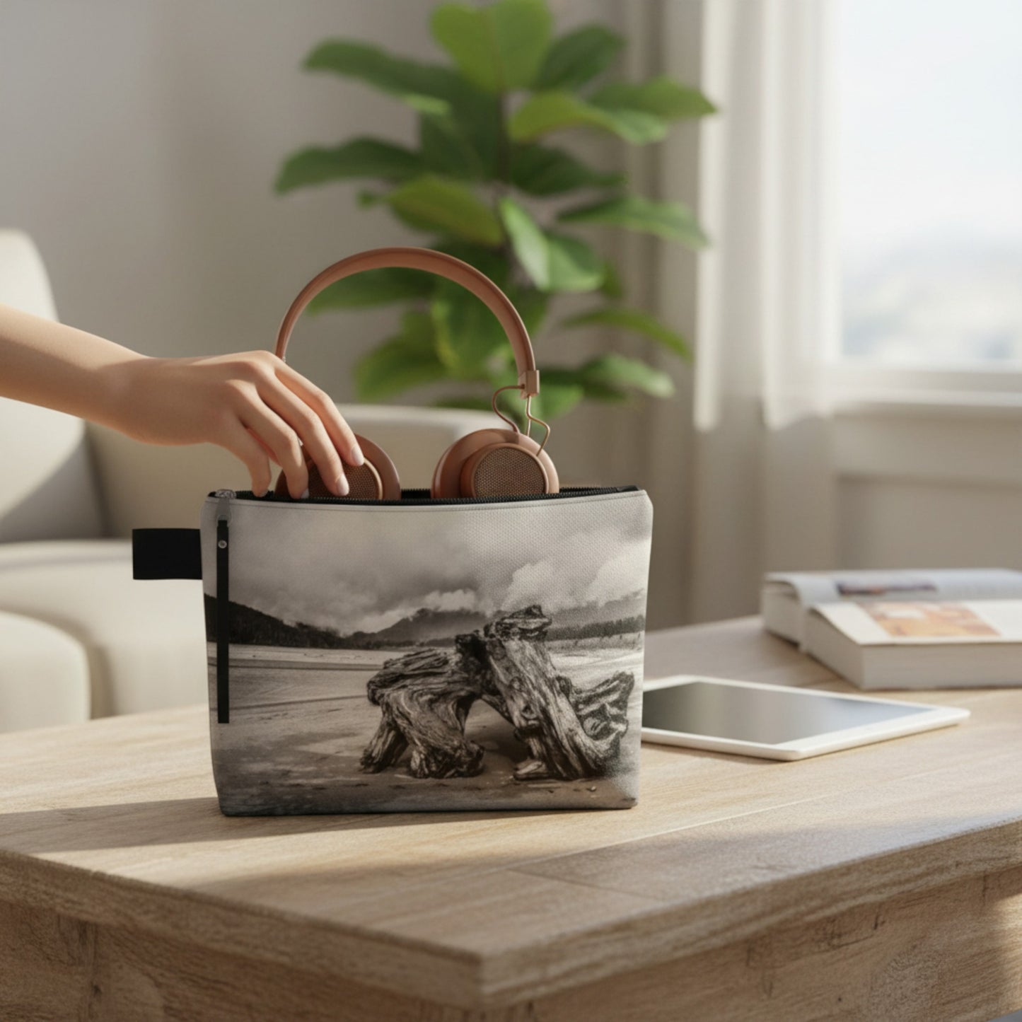 Hand holding a small pouch with a beach design on a wooden table.