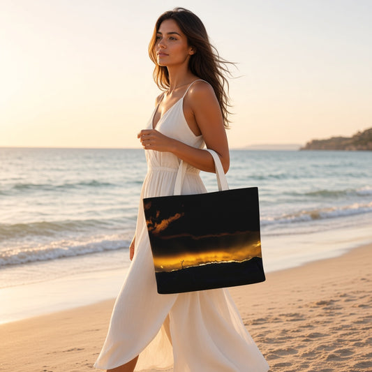 A woman in a white dress walks along a sandy beach at sunset while carrying a large tote bag printed with a dramatic black sky and golden sunset scene.