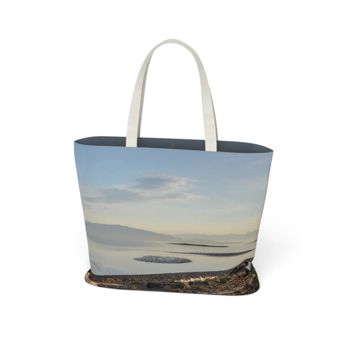 A tote bag featuring a photographic print of a calm lake or sea under a pale sky, with a dark base and two light beige handles, shown on a plain white background.